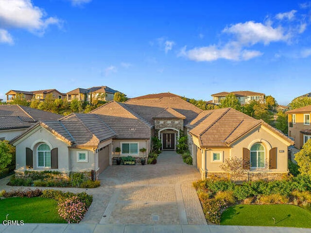 view of front of property with an attached garage, stucco siding, decorative driveway, and a tile roof
