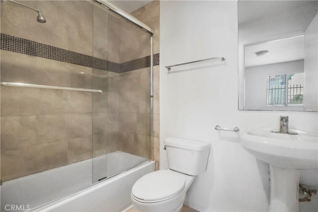 bathroom with toilet, enclosed tub / shower combo, and a sink