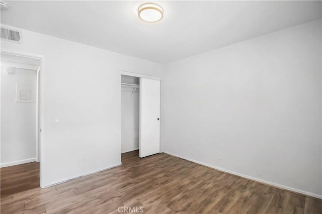 unfurnished bedroom with wood finished floors, a closet, and baseboards