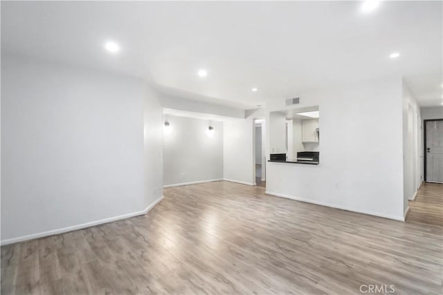 unfurnished living room with light wood finished floors, recessed lighting, and baseboards