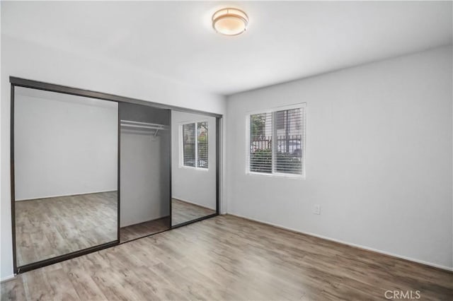 unfurnished bedroom featuring wood finished floors and a closet