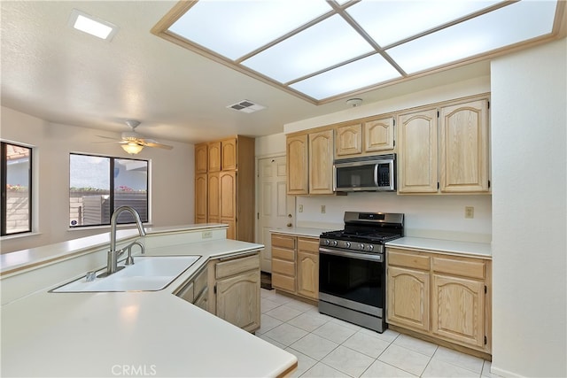 kitchen featuring stainless steel appliances, a sink, light brown cabinetry, and light countertops