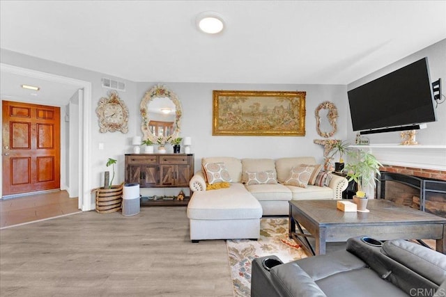 living area with wood finished floors and a brick fireplace