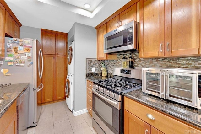 2916 Alanwood Ct, Spring Valley, CA 91978 - kitchen with stainless steel appliances, stacked washing machine and dryer, decorative backsplash, and dark stone counters