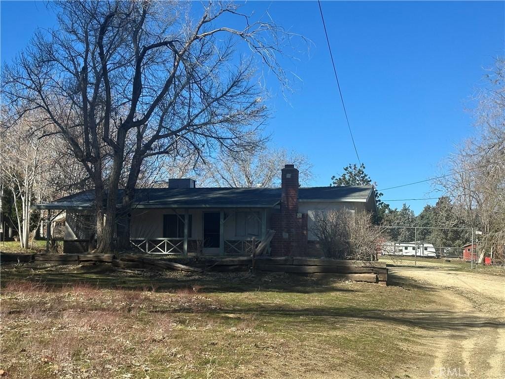 view of side of property featuring a porch, a chimney, and driveway