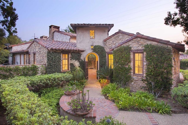 7031 Calle Portone, Rancho Santa Fe, CA 92091 - mediterranean / spanish house featuring stone siding, a chimney, stucco siding, and a tile roof