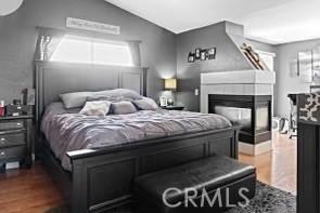 13775 Valera Way, Victorville, CA 92392 - bedroom featuring dark wood-type flooring, vaulted ceiling, and a multi sided fireplace