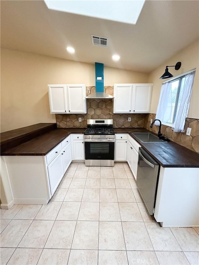 770 Cypress Ln, Blythe, CA 92225 - kitchen with stainless steel appliances, wall chimney exhaust hood, a sink, decorative backsplash, and light tile patterned floors