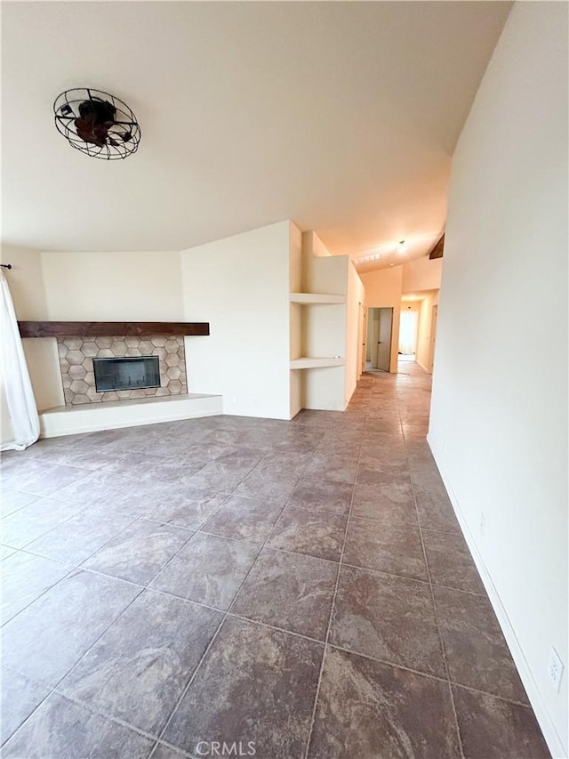 770 Cypress Ln, Blythe, CA 92225 - unfurnished living room with a stone fireplace, lofted ceiling, built in shelves, and baseboards