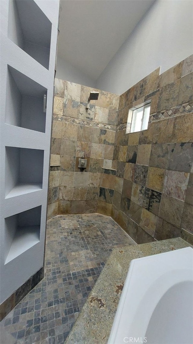 full bath with tiled shower and lofted ceiling