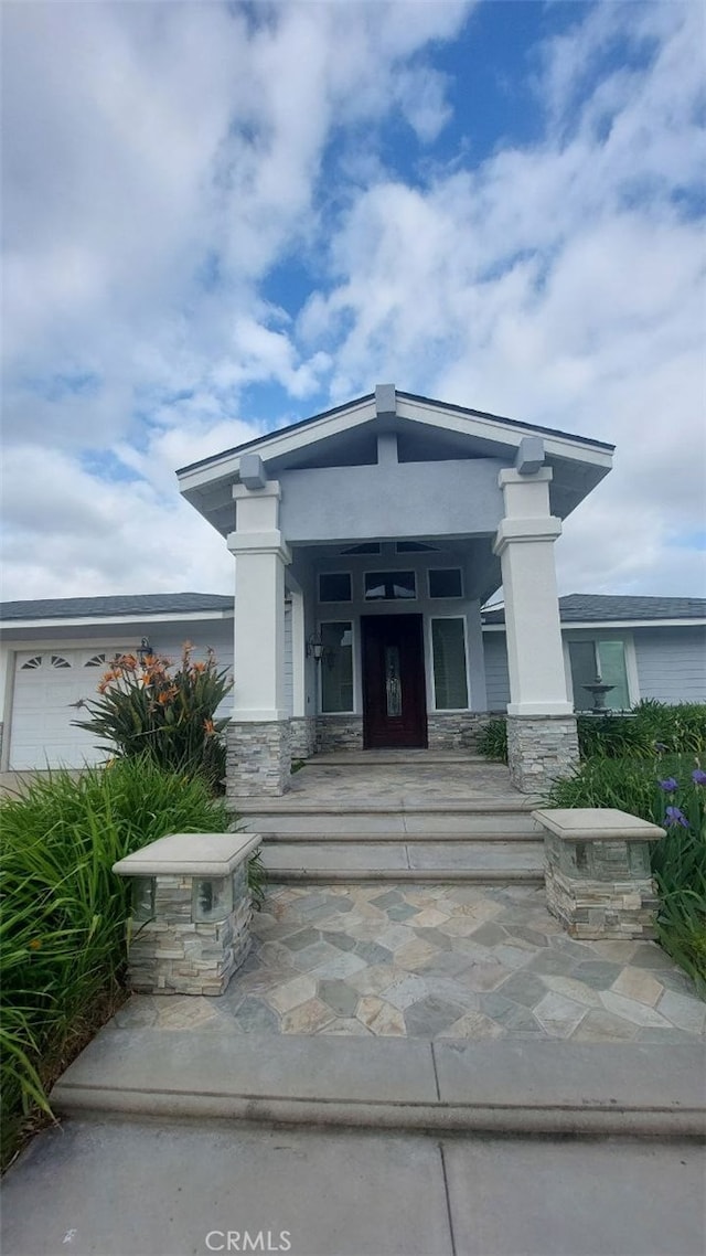 property entrance with stone siding, a porch, and stucco siding