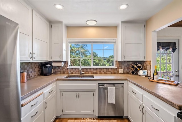 kitchen featuring stainless steel appliances, a sink, decorative backsplash, white cabinets, and recessed lighting