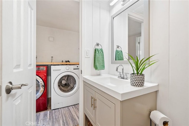 laundry area with washing machine and dryer and light wood-style flooring