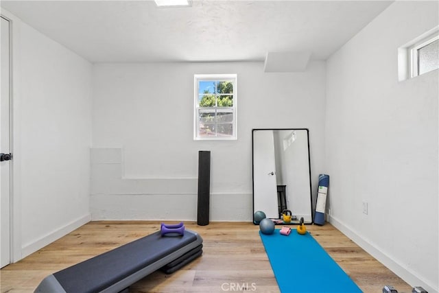 workout room featuring plenty of natural light, wood finished floors, and baseboards