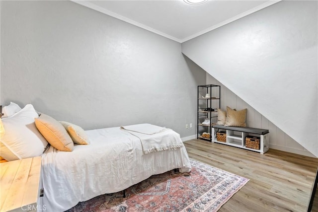 bedroom with wood finished floors, baseboards, and ornamental molding