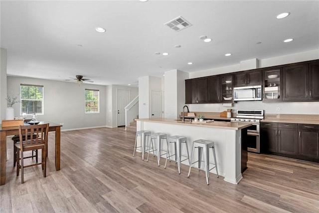 22069 Windham Way, Saugus, CA 91350 - kitchen featuring appliances with stainless steel finishes, a breakfast bar, dark brown cabinets, recessed lighting, and an island with sink