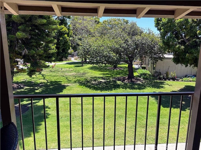 view of grassy yard with a balcony