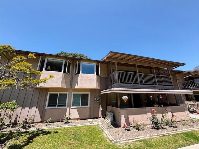 back of house featuring a balcony and stucco siding