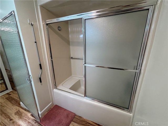 bathroom featuring wood finished floors and enclosed tub / shower combo