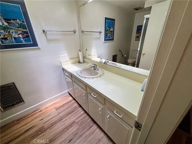 bathroom featuring wood finished floors, toilet, vanity, and baseboards
