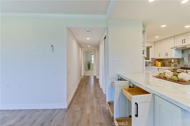 3364 Punta Alta Unit 1E, Laguna Woods, CA 92637 - kitchen with white cabinets, decorative backsplash, light wood-type flooring, baseboards, and light stone counters