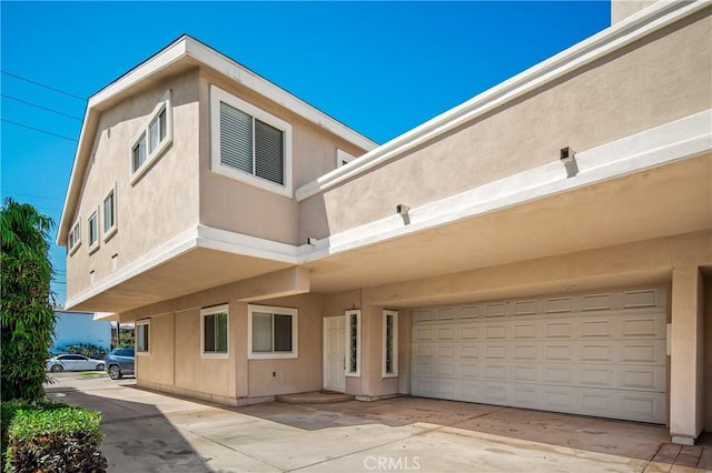 2401 Vanderbilt Ln Unit B, Redondo Beach, CA 90278 - back of house featuring stucco siding, an attached garage, and concrete driveway
