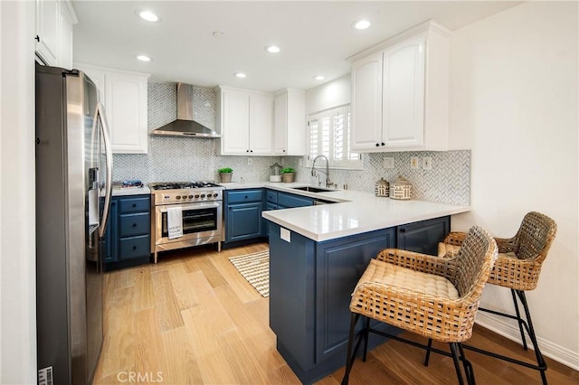 2401 Vanderbilt Ln Unit B, Redondo Beach, CA 90278 - kitchen with wall chimney exhaust hood, stainless steel appliances, a sink, blue cabinets, and a peninsula