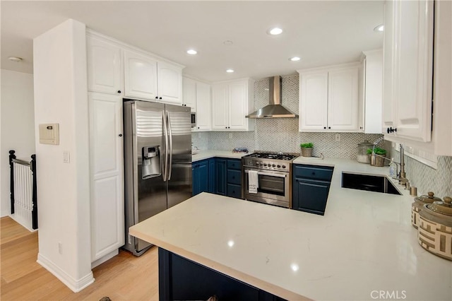 2401 Vanderbilt Ln Unit B, Redondo Beach, CA 90278 - kitchen featuring appliances with stainless steel finishes, wall chimney exhaust hood, a sink, blue cabinetry, and light wood finished floors