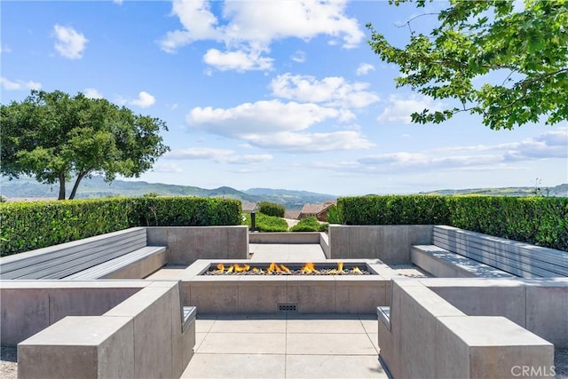 view of patio / terrace with a fire pit and a mountain view