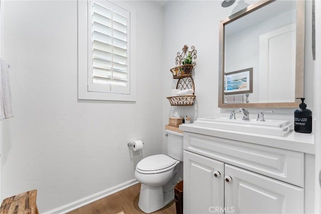 bathroom with wood finished floors, toilet, vanity, and baseboards