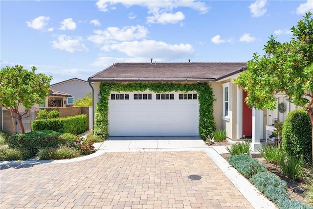 view of front facade with driveway, stucco siding, an attached garage, and a tile roof