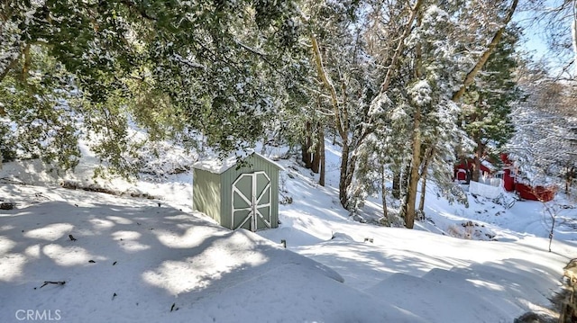 yard covered in snow featuring a shed and an outdoor structure