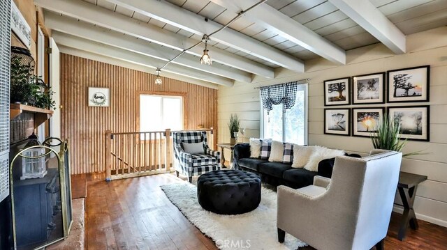 living area featuring hardwood / wood-style flooring, plenty of natural light, wooden walls, and beamed ceiling