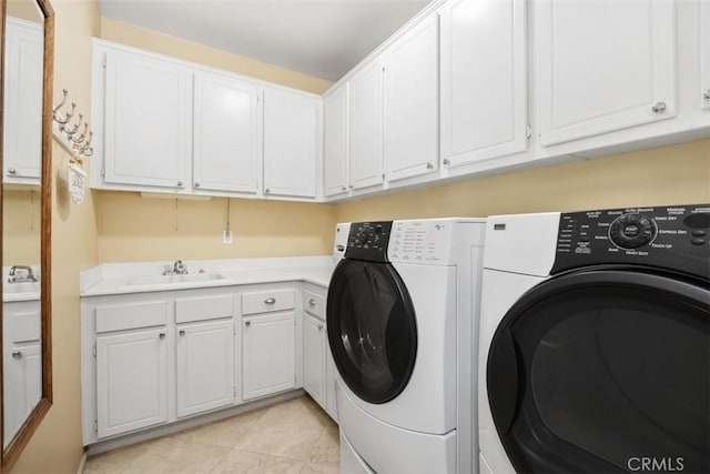 laundry area with washing machine and clothes dryer, cabinet space, and light tile patterned floors