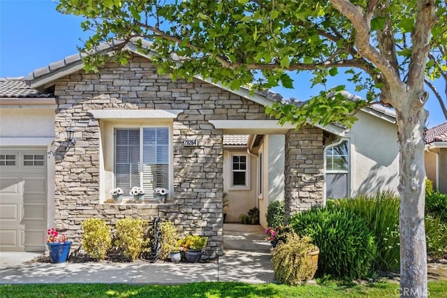 view of front facade with stone siding, an attached garage, and stucco siding