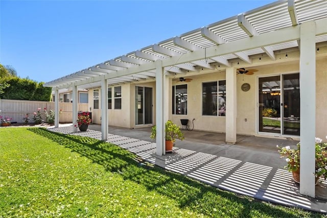 rear view of property featuring a pergola, a ceiling fan, a patio area, and stucco siding