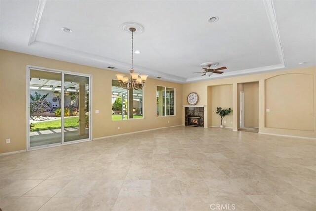 unfurnished living room with a tray ceiling, plenty of natural light, a chandelier, a fireplace, and recessed lighting