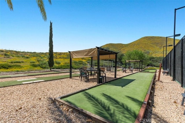 view of community featuring a game area, a mountain view, and fence