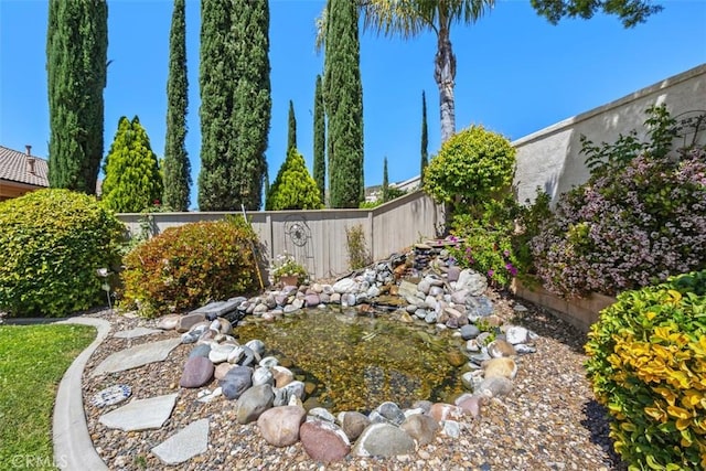 view of yard featuring fence and a small pond