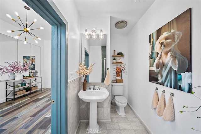 791 Cypress Rd, Lake Arrowhead, CA 92321 - bathroom with a chandelier, toilet, wainscoting, tile walls, and a sink