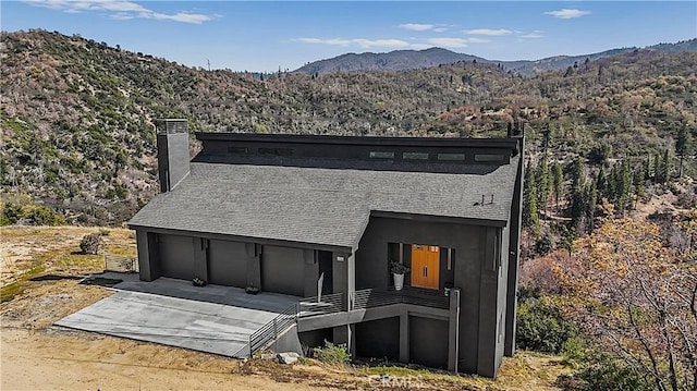 791 Cypress Rd, Lake Arrowhead, CA 92321 - back of property with a chimney, a mountain view, concrete driveway, and a garage