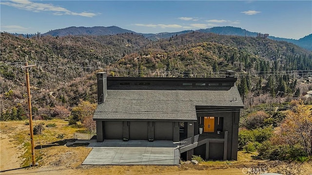 791 Cypress Rd, Cedar Glen, CA 92321 - view of front facade featuring a mountain view, a garage, driveway, a chimney, and a view of trees