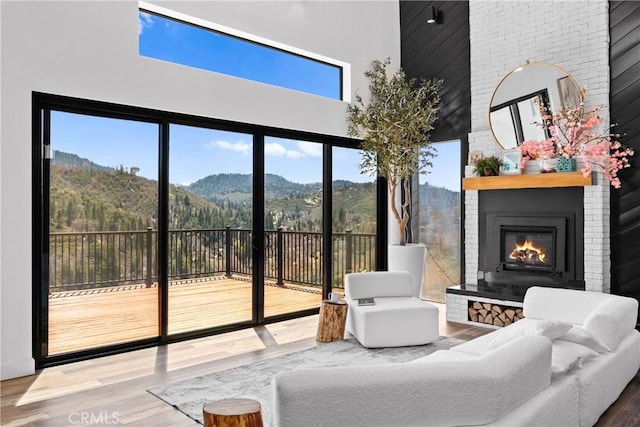 791 Cypress Rd, Lake Arrowhead, CA 92321 - sitting room featuring a towering ceiling, a fireplace, wood finished floors, and a mountain view