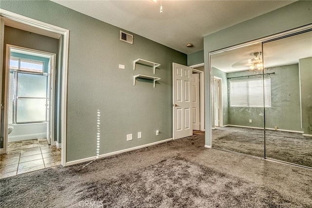 unfurnished bedroom featuring carpet floors, multiple windows, connected bathroom, and a textured wall
