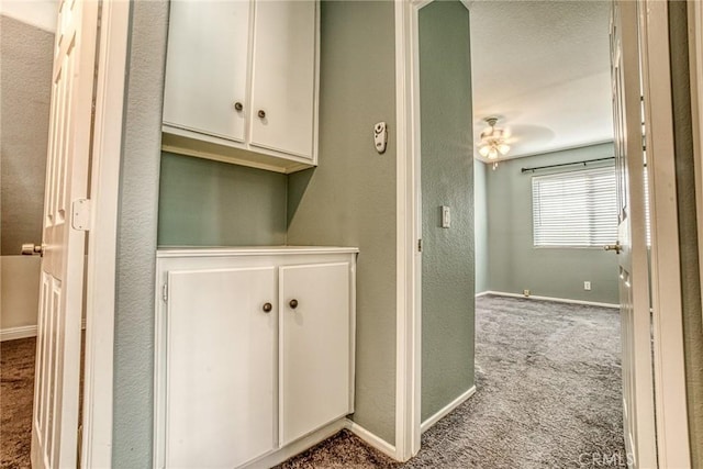 hall with carpet floors, baseboards, and a textured wall
