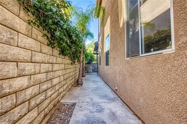 view of side of home featuring stucco siding and a gate