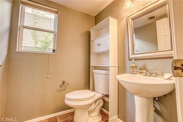 bathroom with toilet, baseboards, and a sink