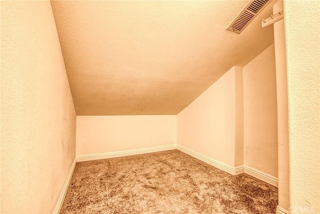 additional living space featuring vaulted ceiling, carpet flooring, a textured ceiling, and baseboards