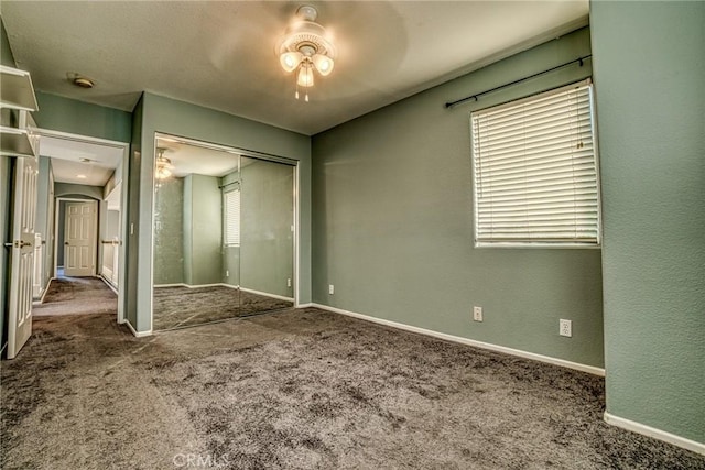 unfurnished bedroom with carpet floors, a closet, baseboards, and ceiling fan