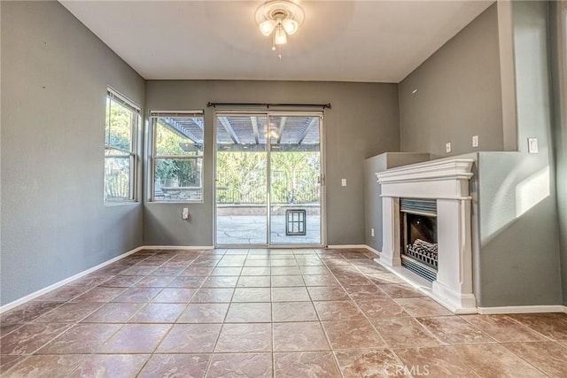 unfurnished living room featuring a fireplace, a ceiling fan, tile patterned floors, and baseboards